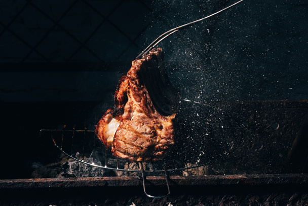 vista close-up de deliciosa carne suculenta com costelas e garfo de carne se preparando na grelha
  - Foto, Imagem