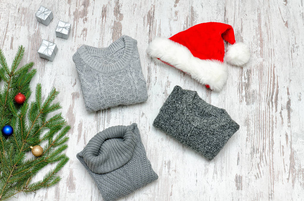 drei graue Pullover, Weihnachtsmannmütze und Tannenzweig - Foto, Bild