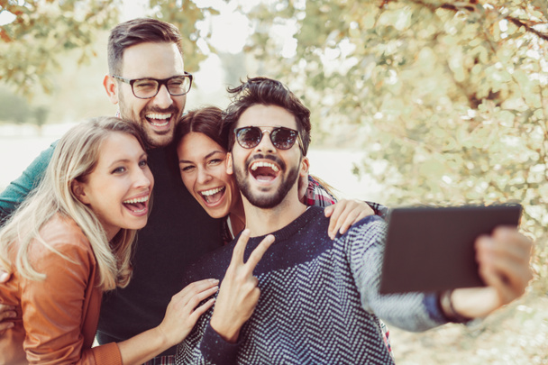 groupe de jeunes amis heureux s'amuser dans le parc de printemps avec tablette numérique et prendre selfie
  - Photo, image