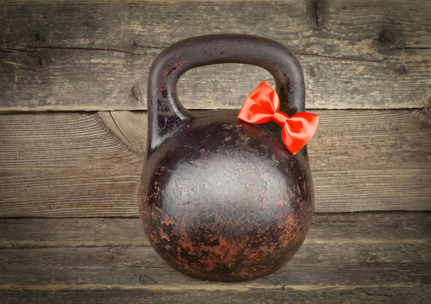 Red bow on Old rusty Kettlebell over wooden table - Photo, Image