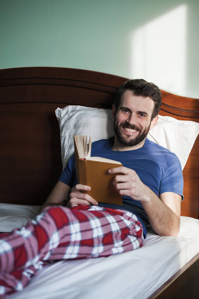 Giovane che legge un libro nella sua camera da letto
 - Foto, immagini