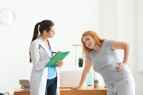 Young female doctor observing overweight woman after exercise in clinic - Foto, Imagem