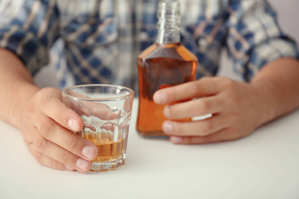 Man with glass and bottle of brandy indoors. Alcohol dependence concept - Photo, image