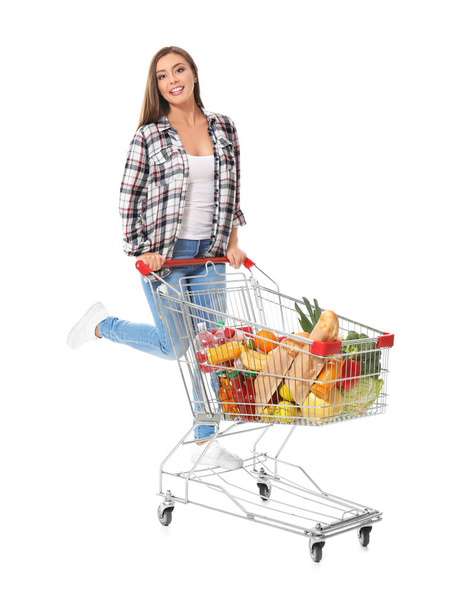 Young woman with full shopping cart on white background - Fotoğraf, Görsel