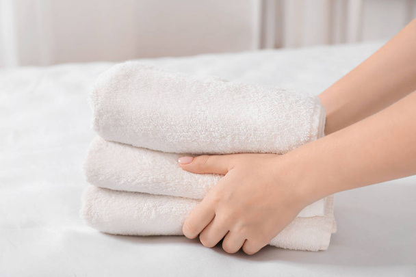 Woman putting stack of towels on bed - Photo, image