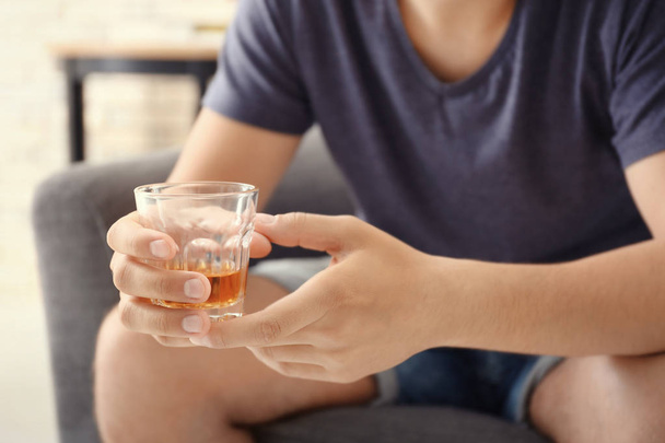 Man with glass of whiskey indoors. Alcohol dependence concept - Foto, Imagen