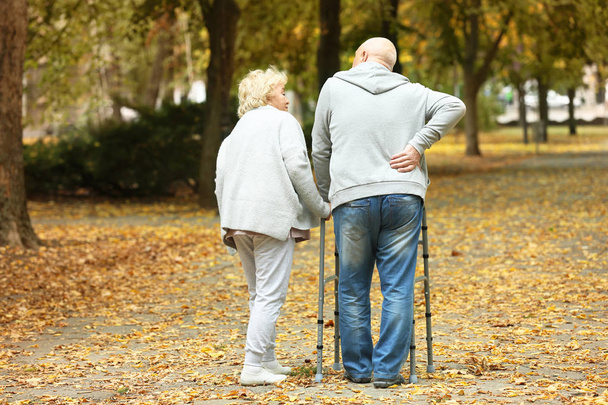 Elderly woman and her husband with walking frame in autumn park - Fotoğraf, Görsel