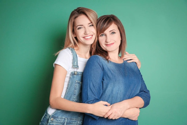 Attractive young woman with her mother on color background - Fotoğraf, Görsel
