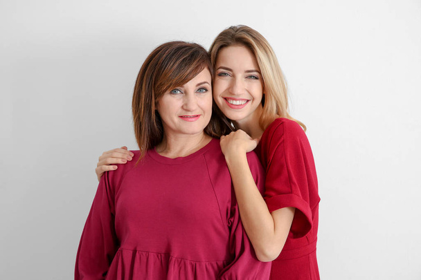 Attractive young woman with her mother in matching dresses on white background - Φωτογραφία, εικόνα