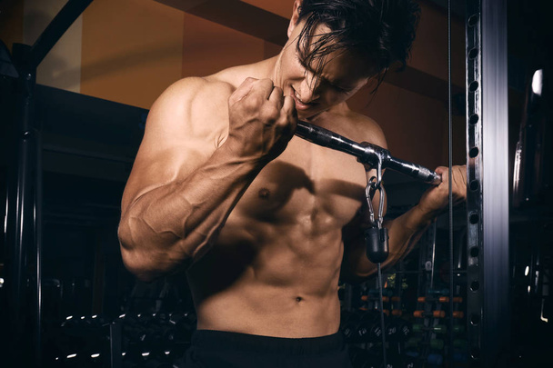 Young man training on exercise machine in gym - Фото, зображення
