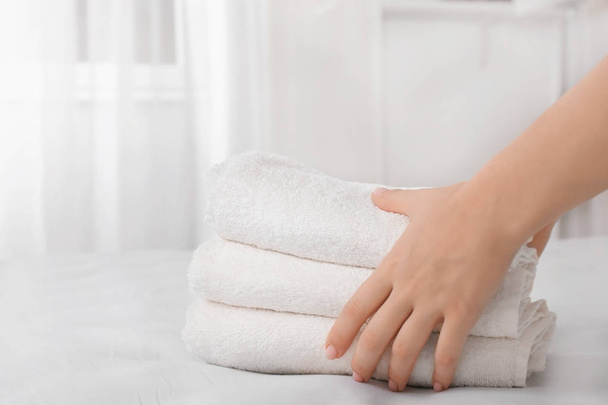 Woman putting stack of towels on bed - Foto, Imagen