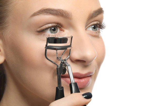 Beautiful young woman with eyelash curler on white background - Foto, imagen
