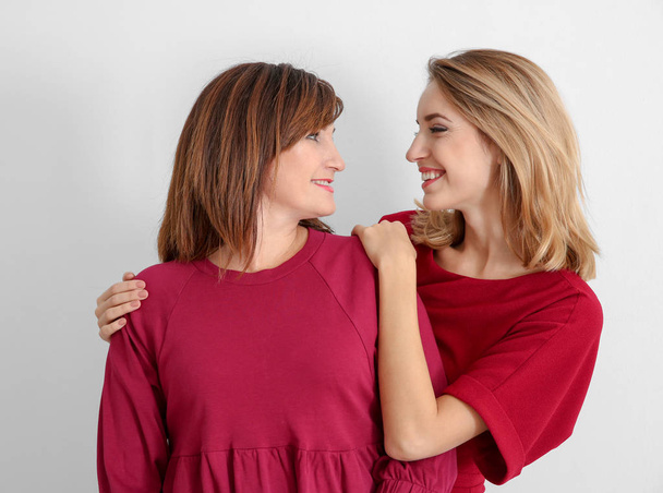 Attractive young woman with her mother in matching dresses on white background - Foto, immagini