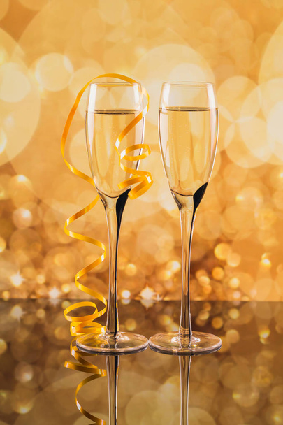 Two glasses of champagne with golden light bokeh on background. - Фото, зображення