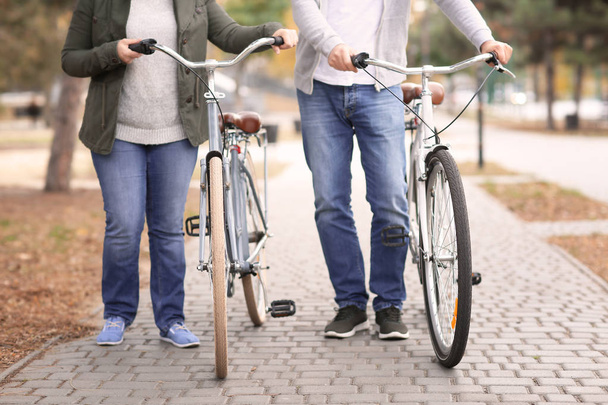 Senior couple walking with bicycles in park - Photo, image