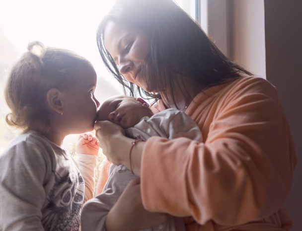 eine junge Mutter genießt die ersten Tage der Mutterschaft mit ihrem Kind im Arm  - Foto, Bild
