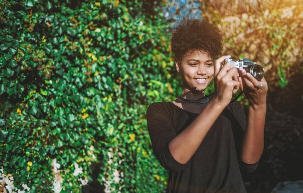 Black girl using vintage film cam in the garden - Zdjęcie, obraz