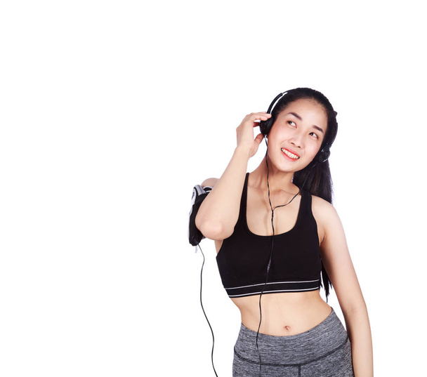 smiling fitness woman listening to music with earphones isolated - Foto, Imagen