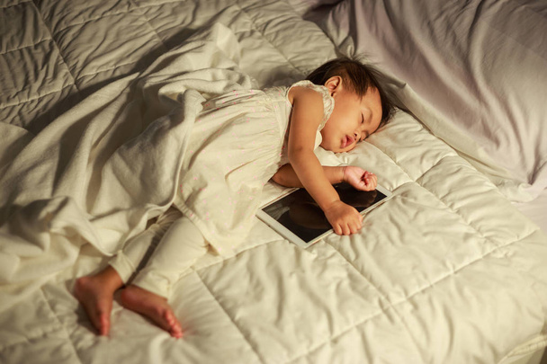 vauva nukkuu sängyssä pelaamisen jälkeen tabletti
 - Valokuva, kuva