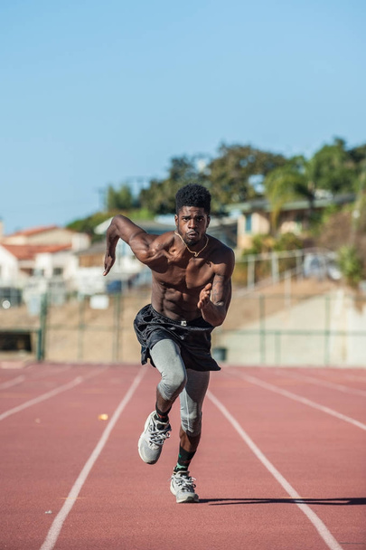 Előrehajolva a lendületét míg futásnak Lane stadion pályán izmos jamaicai atléta. - Fotó, kép