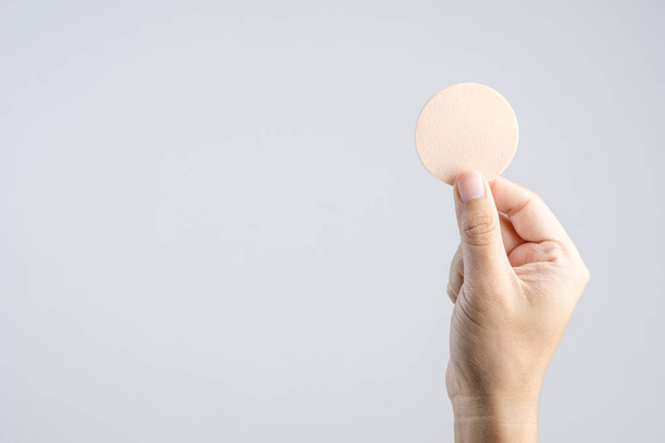 Hand holding round brown face sponge for cosmetic on white background - Zdjęcie, obraz
