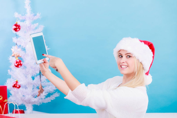 Woman in Santa hat sitting holding tablet - Foto, Imagen