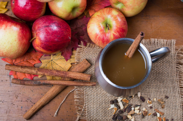 Top view of apple cider in a cup with apples and cinnamon sticks - Photo, Image