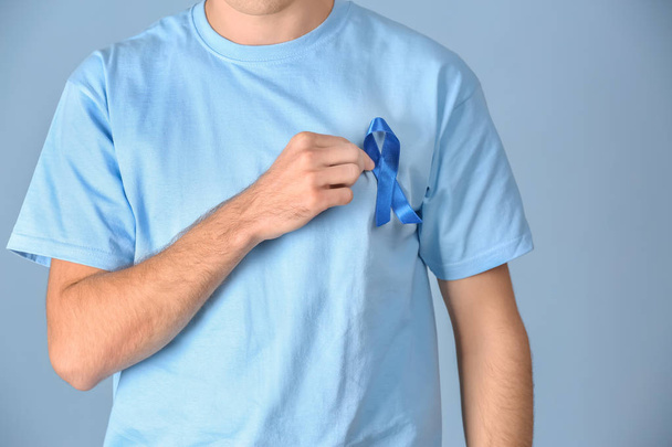 Young man wearing t-shirt with blue ribbon on color background, closeup. Prostate cancer awareness concept - Фото, зображення