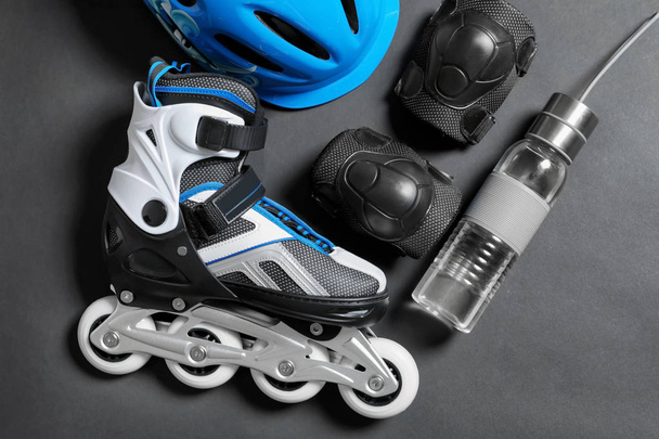 Rollschuh, Knieschoner und Wasserflasche auf grauem Hintergrund - Foto, Bild