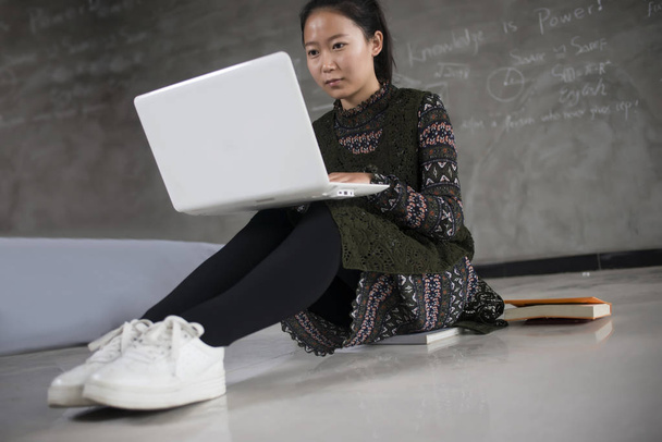 Студентка работает на полу, чтобы использовать ноутбук
 - Фото, изображение