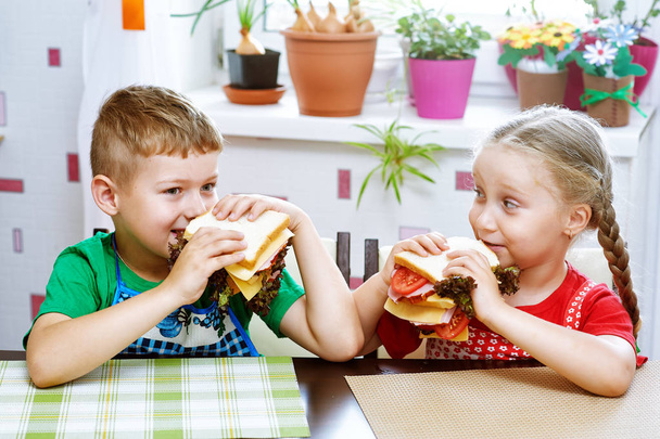 Kinderen eten ontbijt sandwiches. Grappige kinderen maken broodjes - Foto, afbeelding