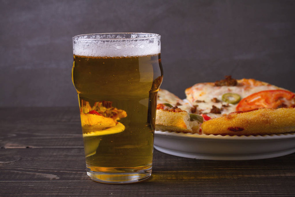 Beer and pizza on dark wooden background. Ale and food - Photo, image