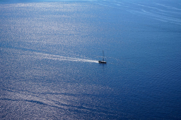 Vista del vasto paisaje marino azul del Egeo copia el fondo del espacio con el barco de vela y el reflejo de la luz solar del agua del océano desde el pueblo de Oia
 - Foto, imagen