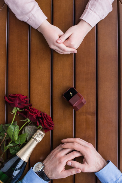 Oříznout obrázek pár sedí u stolu s snubní prsten mezi nimi - Fotografie, Obrázek