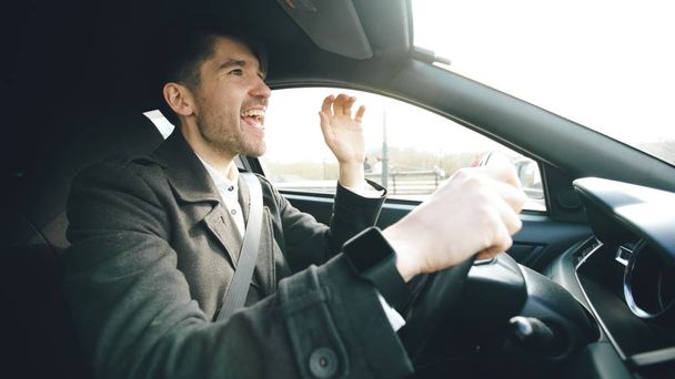 Happy handsome businessman driving car and singing. Man is happy after making deals and drives home - Fotoğraf, Görsel