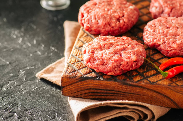 Raw ground meat beef burgers on a wooden board. Close up and cop - Photo, image