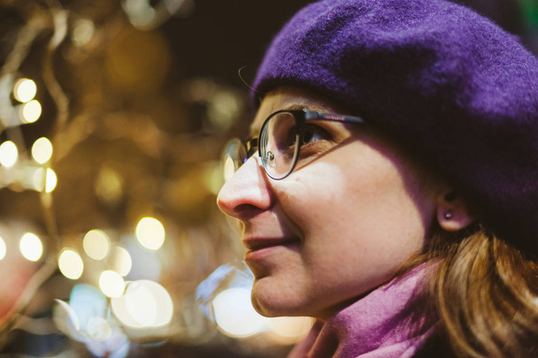 Ritratto di bella donna francese che indossa berretto alla moda con luci bokeh sfocate del mercatino di Natale sullo sfondo
 - Foto, immagini
