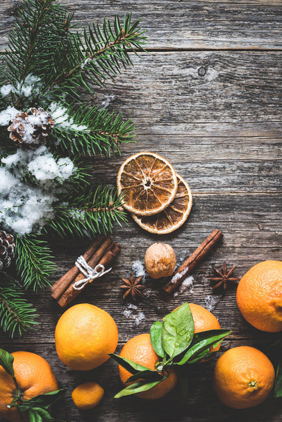 Winter or Christmas composition with clementines, fir tree branch, spices and snow - Foto, afbeelding