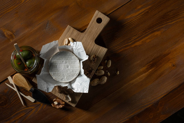 delicious camembert cheese, herbs, nuts and knife on wooden tray, top view with copy space - Φωτογραφία, εικόνα