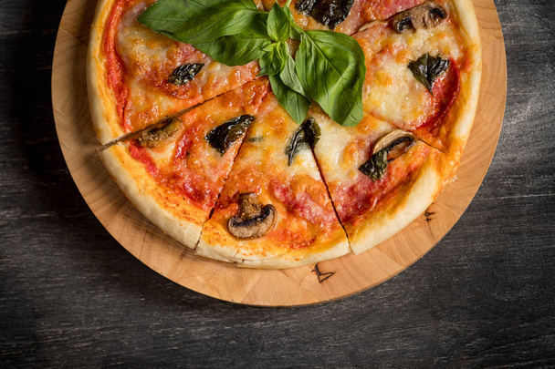 domácí pizza s houbami a bazalkou na dřevěné desce, pohled shora s kopií prostor - Fotografie, Obrázek