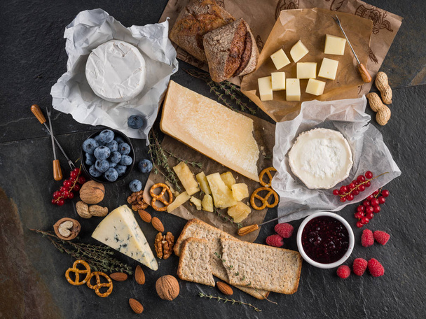 cheese, berries, pretzels and bread on dark stone table, top view  - 写真・画像