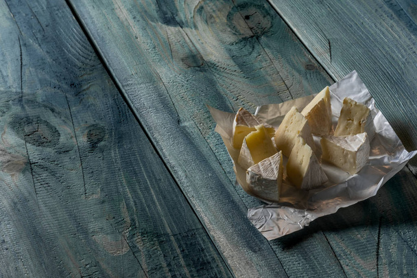 rustic flat lay with sliced camamber cheese on blue wooden background, top view with copy space - Foto, immagini