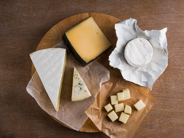 assorted cheese slices on wooden board, top view  - Fotó, kép