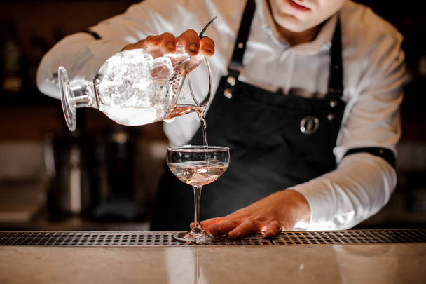 Bartender adding vodka into a cocktail glass in the dark light - Photo, Image