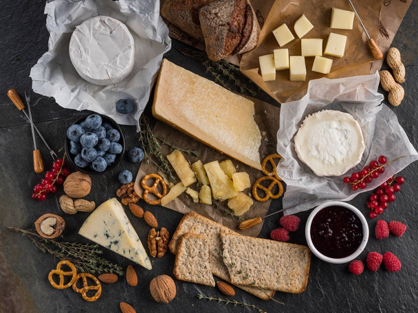 válogatott sajt, jam friss bogyós gyümölcsök a kő sötét tábla - Fotó, kép