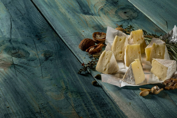 brie cheese slices, herbs and nuts on blue wooden background, top view with copy space - Foto, Bild