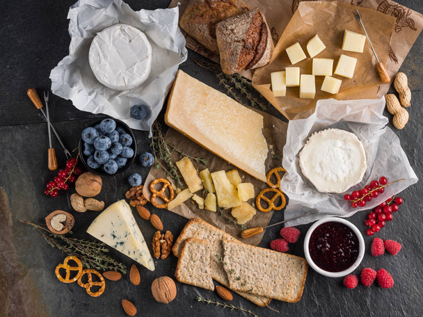 cheese, berries, pretzels and bread on dark stone table, top view  - 写真・画像