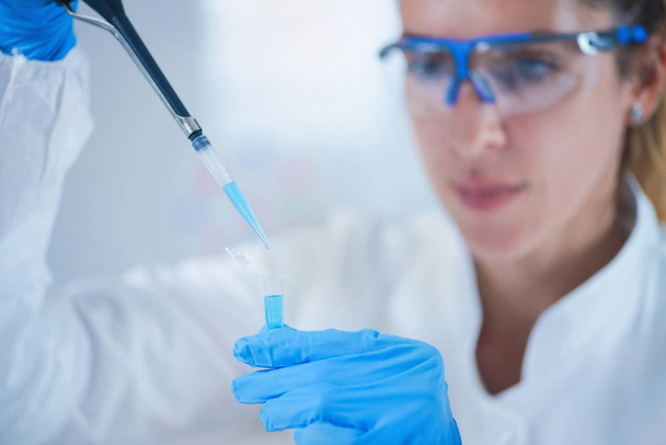 Young female scientist using pipette in research laboratory - Photo, image