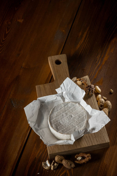 rustic flat lay with brie cheese on cutting board with nuts, top view with copy space - Фото, зображення