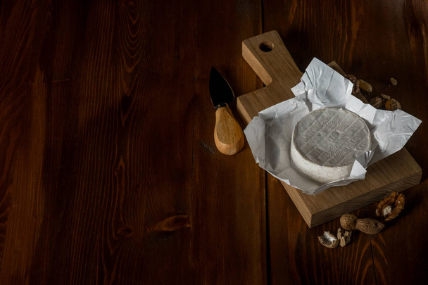 brie cheese on wooden cutting board with nuts and knife, top view with copy space - Fotografie, Obrázek